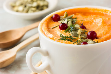 Pumpkin soup and organic pumpkins on rustic wooden table. Seasonal autumn food - Spicy pumpkin soup with thyme and pumpkin seeds.