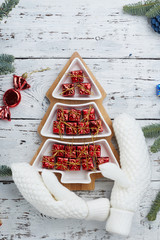 lots of little red gift boxes in the shape of a Christmas tree on a white wooden background. Fir branches on the edge of the frame. The concept of Christmas composition. vertical frame