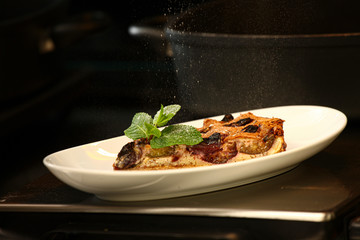 cropped view of woman powdering traditional homemade fruit cake with icing sugar