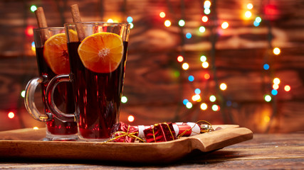 Christmas mulled wine red in a glass with a stick of cinnamon and a piece of orange on a background of twinkling lights