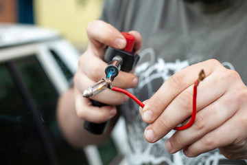 Repair wires. A man checks the wires with a tool. Spare part in the car. Hands of the master at work.