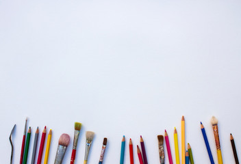 a painting knife, some brushes and colored pencils on a white paper 白い紙の上にペインティングナイフと絵筆と色鉛筆いろいろ