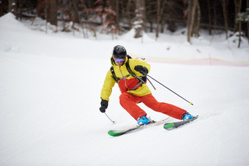 Young skier performing skiing trick. Ski training during snowfall. Carving skiing technique. Winter activities, freestyle, adventure, thrill concept