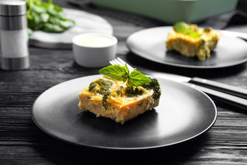 Tasty broccoli casserole served on black wooden table