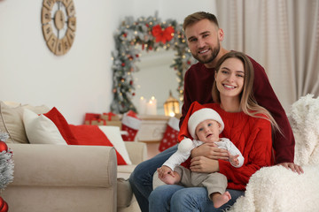 Happy family with cute baby in room decorated for Christmas holiday