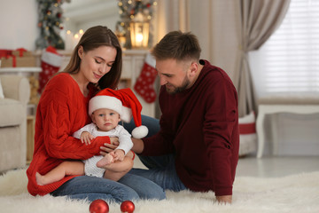 Obraz premium Happy family with cute baby in room decorated for Christmas holiday