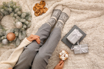 Fototapeta na wymiar Young woman with cocoa and cookies sitting on light blanket, top view. Christmas holiday