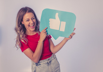 Happy young woman holding Like symbol in internet networking and social media notification icons