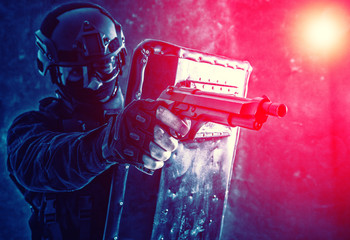 SWAT team fighter aiming pistol from behind shield