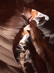 Looking up at Low Antelope canyon, eroded red sandstone walls, sun light falling directly above