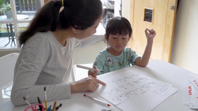 happy mother teaching her daughter the basic to read and write at home. toddler kindergarten student