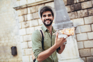 Young handsome casual man eating pizza outdoor