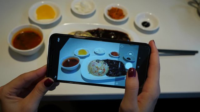 Woman take pictures of cheap small meal, set menu served in restaurant at lunch time. Stir fried rice with seafood, cup of soup and small plates, Korean-style serving of meal
