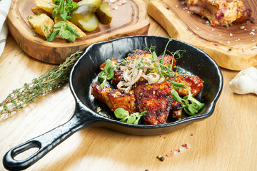 Grilled chicken wings in honey and beer sauce served in a decorative pan with herbs. Close up, selective focus. Wooden background. Food photo