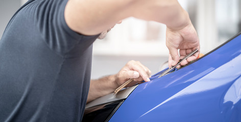 Mann foliert ein Auto mit blauer Folie