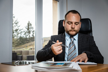 Concentrated young businessman writing documents at office desk