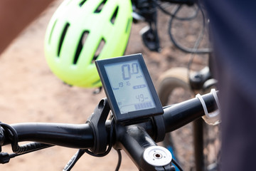 Close-up view of the electronic device of an electric bike. Yellow helmet on background
