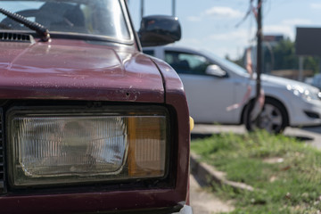 Close-up of the headlights of an old vintage car on a street on a summer day