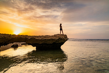 Beautiful girl in dress on the rocky beach at sunset. Red sea