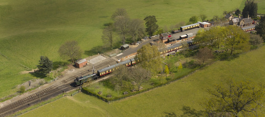 Steam locomotive train parked at English countryside railway station aerial