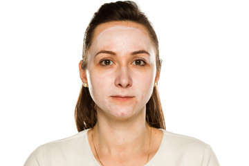 Young woman posing with face cream on white background