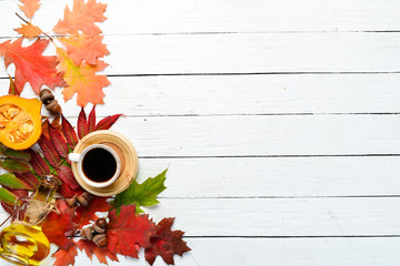 Autumn composition: A cup of coffee and colored autumn leaves. flat lay. On a white wooden background. Top view. Free space for your text.
