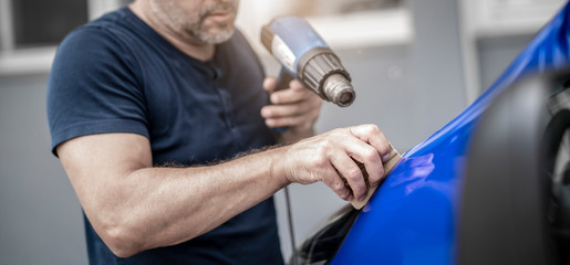 Mann foliert ein Auto mit blauer Folie