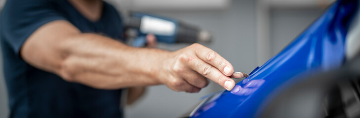Mann foliert ein Auto mit blauer Folie