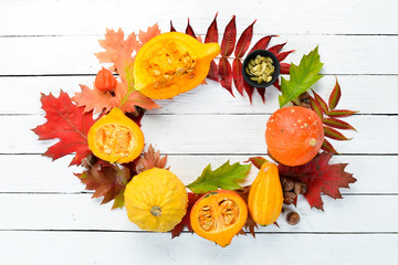 Fresh colored pumpkins and colored autumn leaves. Autumn vegetables. flat lay. On a white wooden background. Top view. Free space for your text.