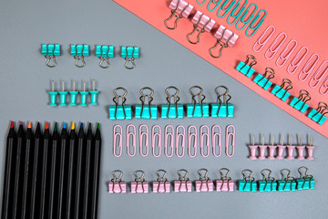 Binder clip and office supplies on a gray and pink background. Business career or education
