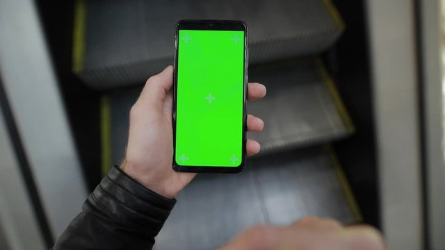 POV, male hand using smartphone with green screen chroma key in the escalator of shopping mall