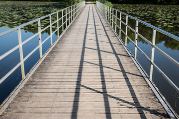 un pont de bois et de métal traversant un étang.
