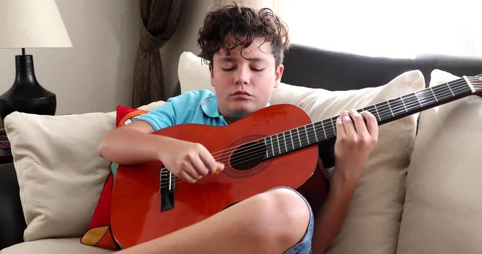 Young boy musician practicing with guitar at home