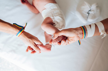 Two women linked hands with a pulse pride and a baby in the hospital