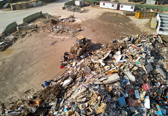 Aftermath of gota fria - cold drop extreme weather floodwaters disaster 2019 in Orihuela coast and Torrevieja, Alicante, Spain. Aerial photography excavator disposing of flooded personal items things