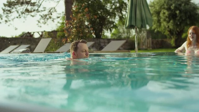 a young man is swimming in a beautiful outdoor pool of an exquisite hotel surrounded by nature - ein junger Mann schwimmt in einem Pool eines exquisiten Hotels in ländlicher Lage 4K ProRes Footage