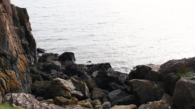 Edge of ocean water and rocks in Aberdour in Scotland. Aberdour is a scenic and historic village on the south coast of Fife, Scotland.