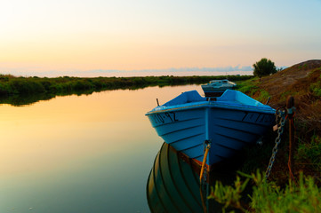 abandoned blue fishing boat at dawn in ebro delta park in catalunya, a quiet scene with warm colors...