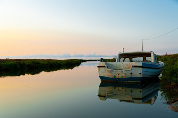 Fototapeta na wymiar lonely abandoned fishing boat at sunrise in ebro delta park in catalunya, a quiet scene symbol of loneliness and peace of mind