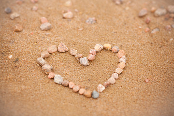 Fototapeta na wymiar Love on the beach. Heart of stones in the sand. Concept on the theme of love, Valentine's Day, tourism and beach holidays. Romance and relationship, a symbol of love in the sand with copyspace.
