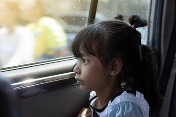 Fototapeta na wymiar Little girl looking out of the car window wearily due to traffic jams.