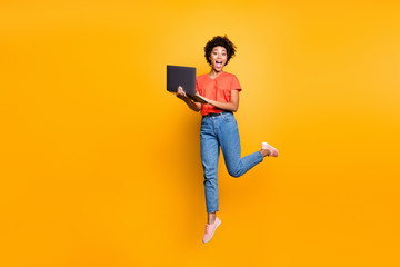 Full size photo of amazed crazy curly brown hair girl use her laptop have notification in feednews jump scream omg wear denim jeans red t-shirt lifestyle sneakers isolated yellow color background