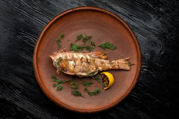 Grilled sea bass on a beautiful clay plate.