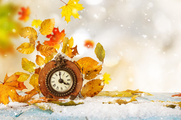 Autumn time change concept. maple leaves and vintage clock on a old wooden background