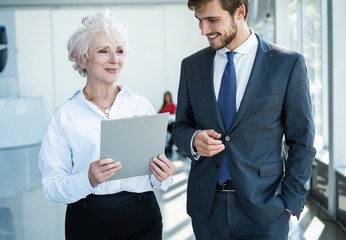 Obraz premium Senior mature caucasian female executive ceo discuss report with young colleague