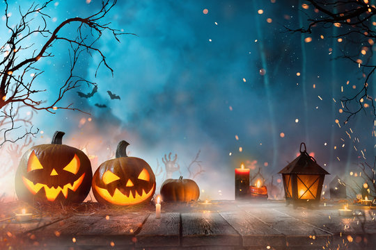 Halloween pumpkins on dark spooky forest with blue fog in background.