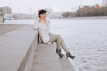 Young beautiful stylish woman in white wool coat walking down the street. Plus size short hair adult girl posing alone.