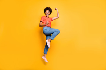 Fototapeta na wymiar Full length body size photo of cheerful cute black girlfriend jumping up wearing jeans denim t-shirt footwear rejoicing isolated over yellow vivid color background