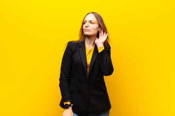 young pretty businesswoman looking serious and curious, listening, trying to hear a secret...