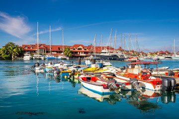 Fototapeta na wymiar Luxury yachts and Boats in sunny summer day at marina of Eden Island, Mahe, Seychelles